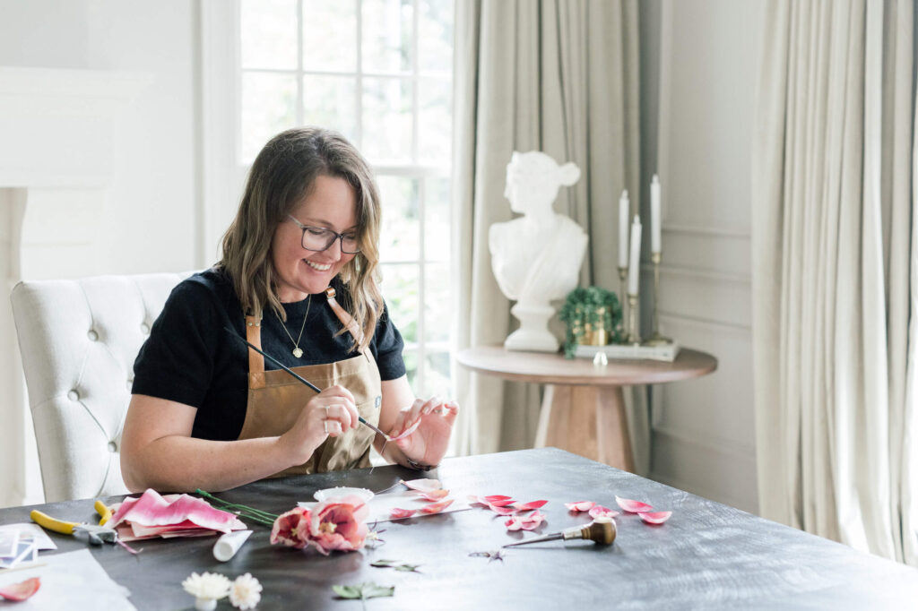 Jenn smiling while painting the petals of a paper tulip